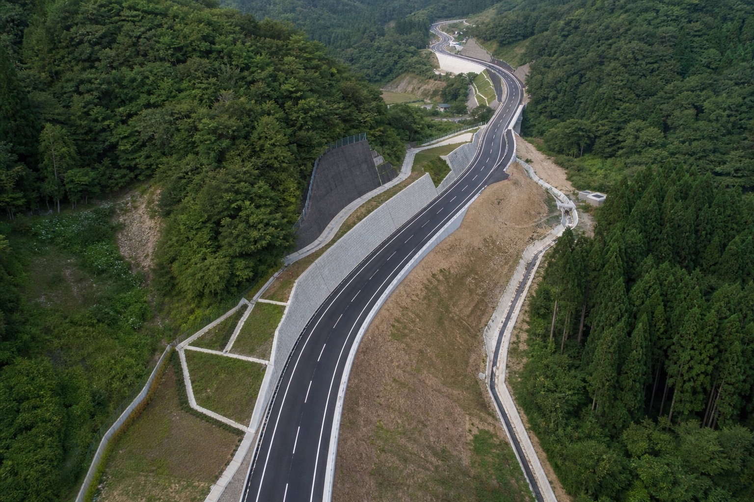 山間を縫って延びる舗装道路の上空からの全景